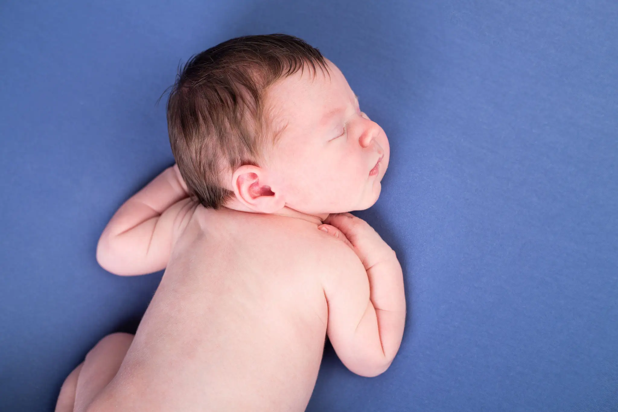 Photo bébé endormi sur le ventre avec fond bleu par la photographe Julie Kirtz