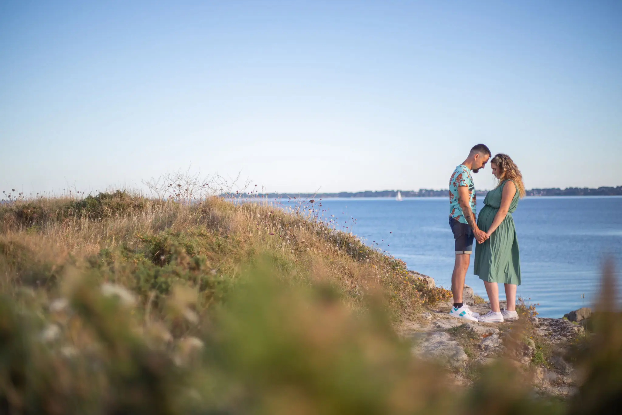 Photo de femme enceinte et future papa à la plage face à la mer