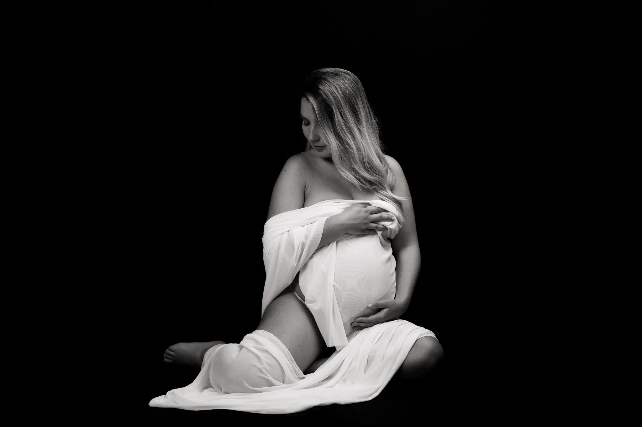 Photo de femme enceinte dans un drap blanc, en noir et blanc
