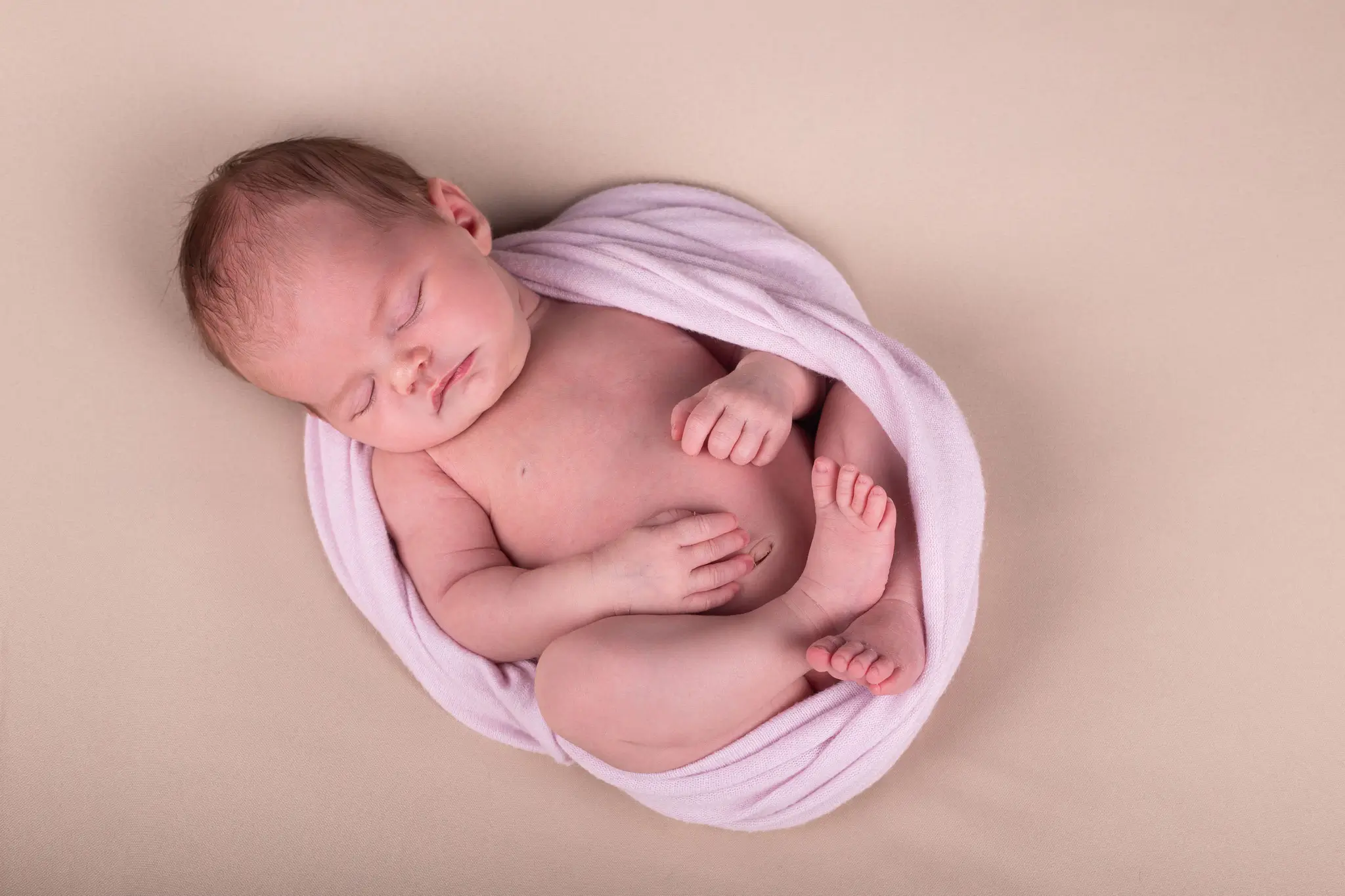 Séance photo bébé endormi sur le dos emmailloté dans un wrap par la photographe Julie Kirtz