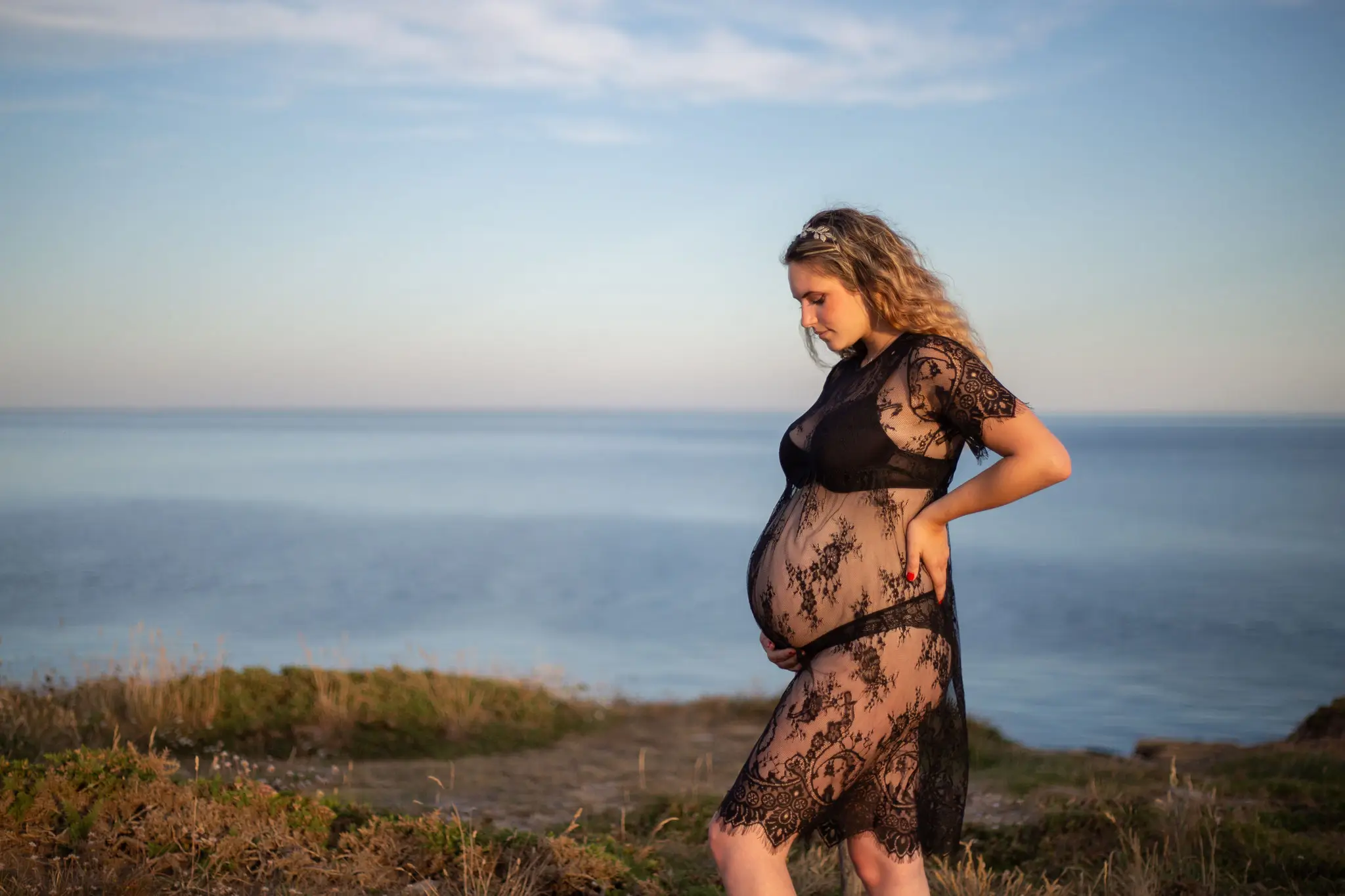 Femme enceinte face à la mer sur la plage