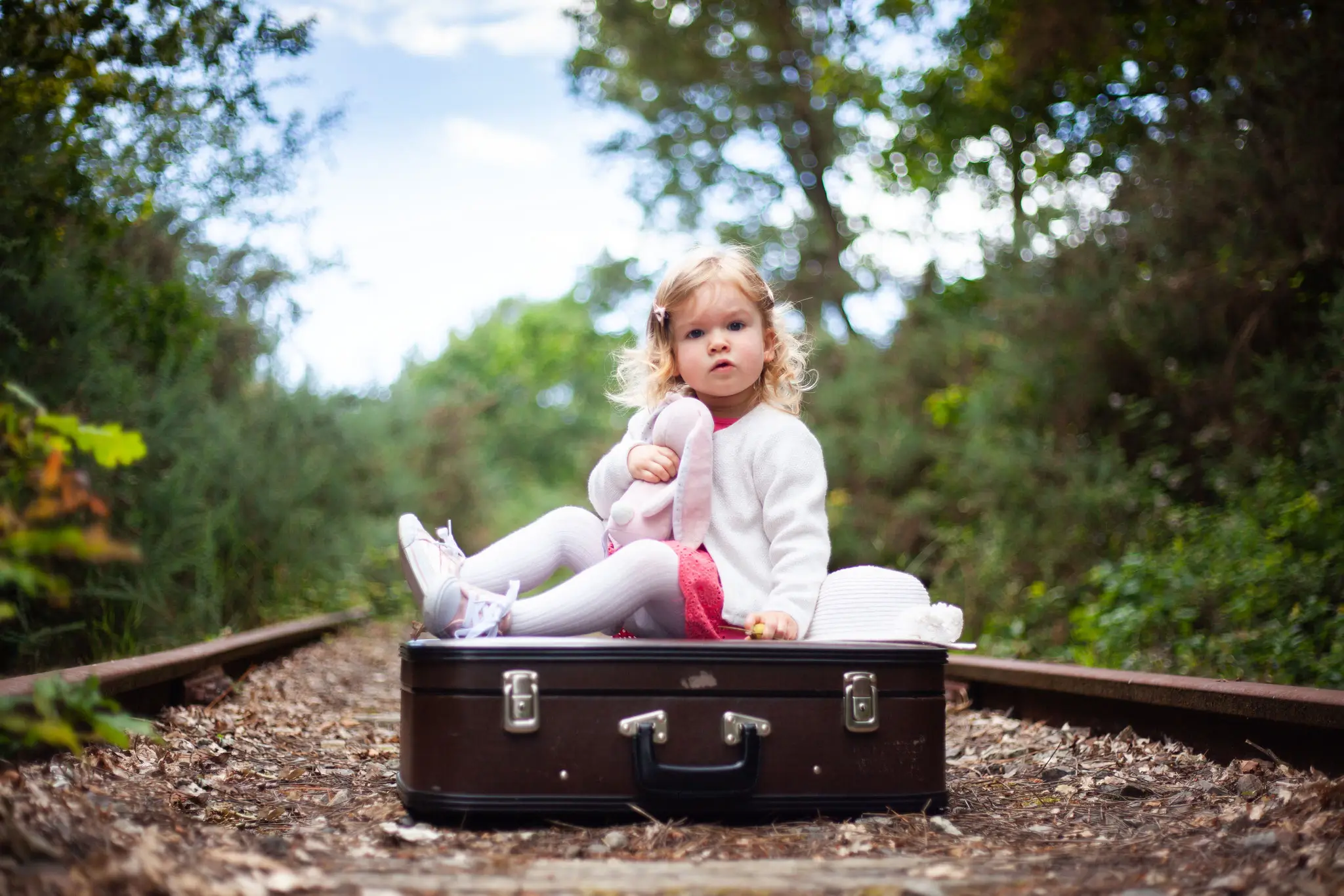 Jolie petite fille sur une valise avec son doudou