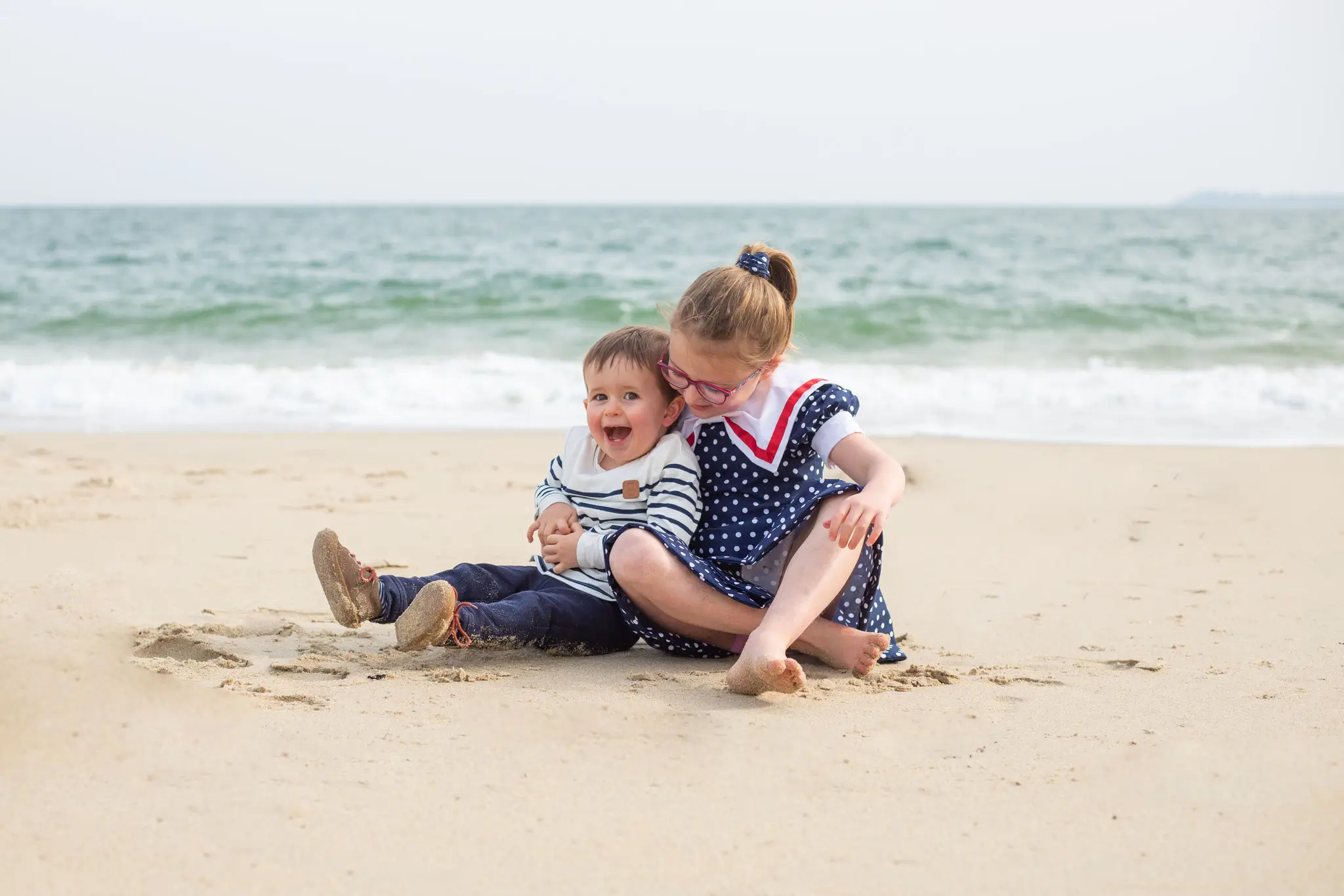 Séance photo frère et sœur tout sourire à la plage