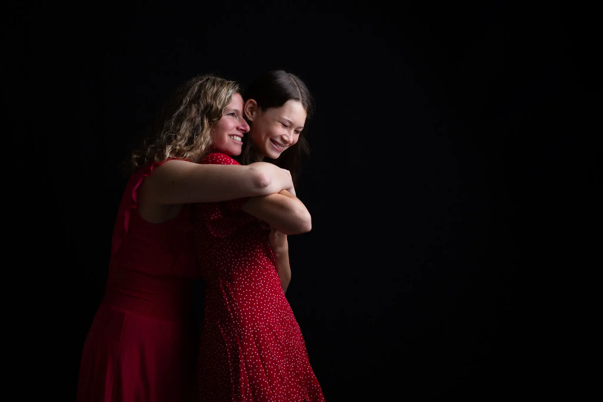 Photo d'une maman et sa fille tout sourire en séance photo sur fond noir