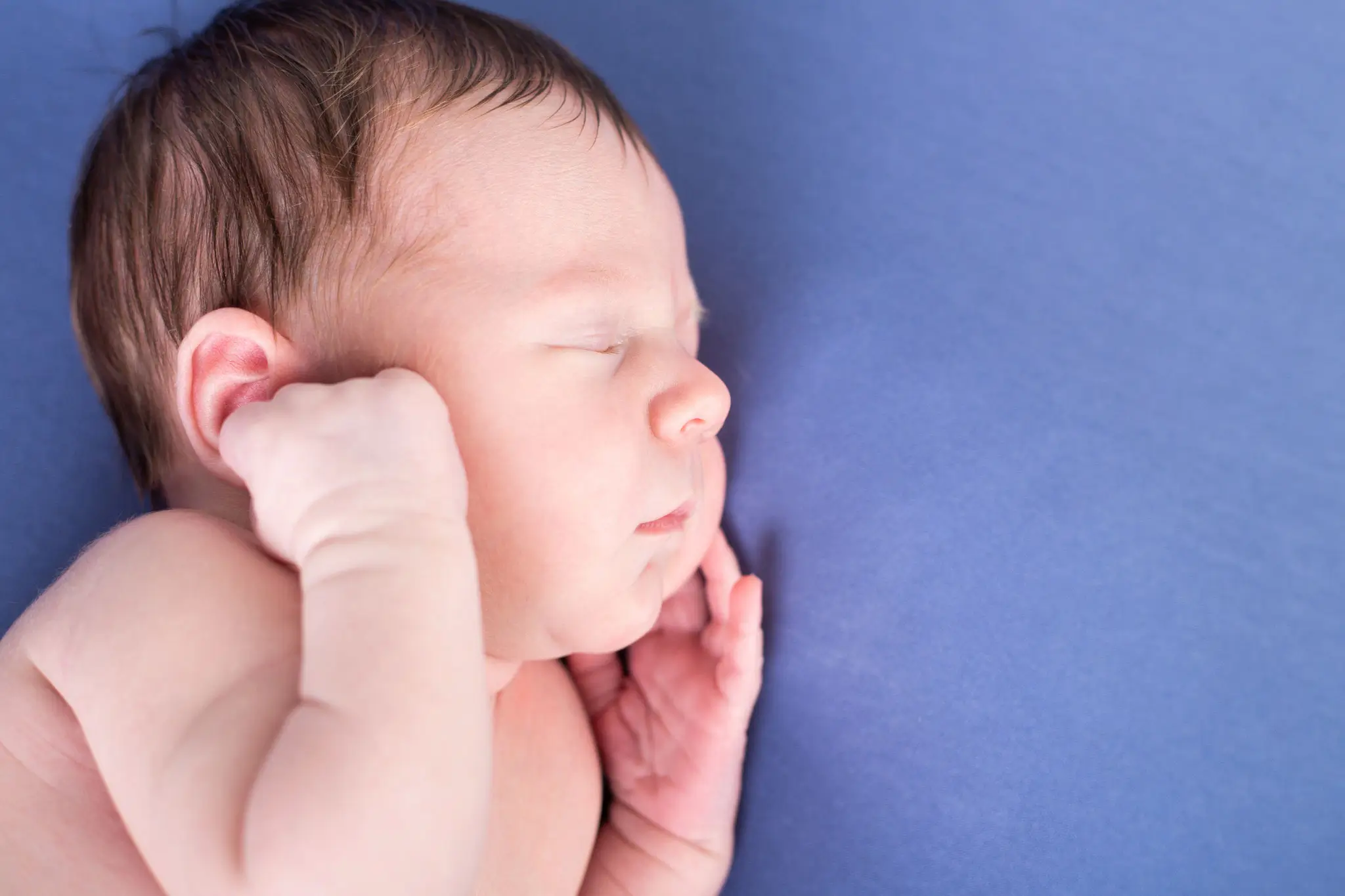 Séance photo bébé endormi sur le côté sur un drap bleu par la photographe Julie Kirtz