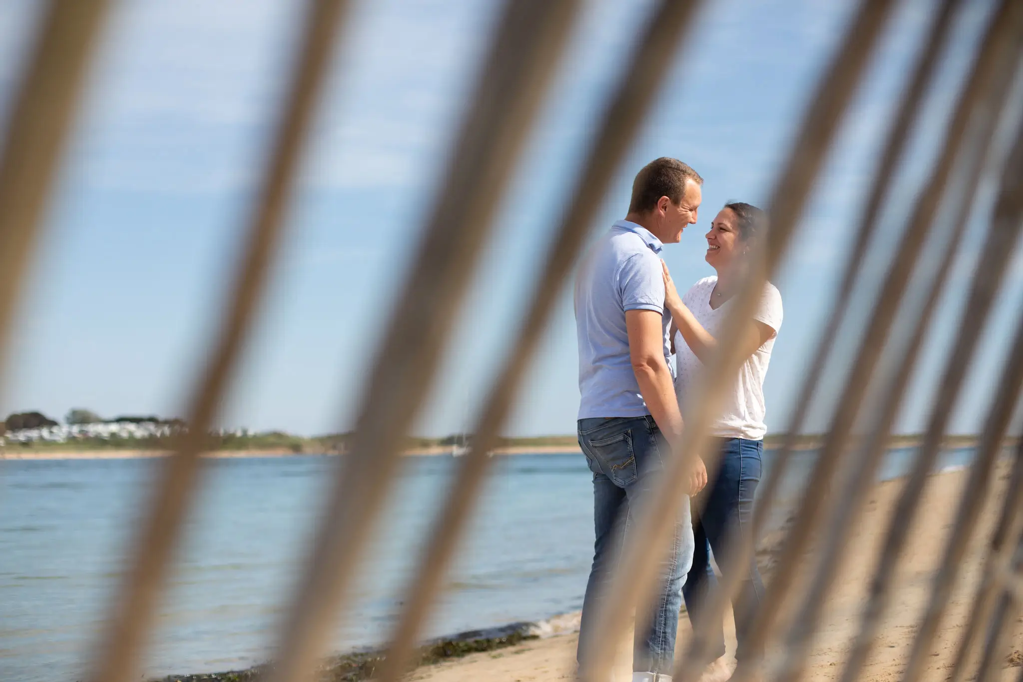 Photo d'un couple qui se regarde avec amour, la plage en arrière-plan